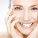 women smiling with hands on her face with beautifully healthy and young skin from laser treatments