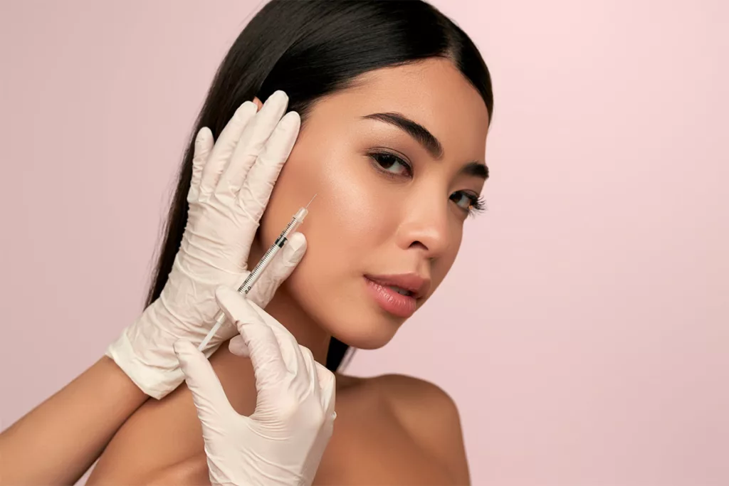 A portrait of a young woman recieving a botox injection in her cheek