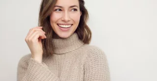 A smiling woman in a beige sweater against a neutral background