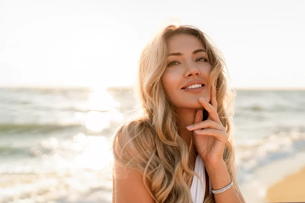 Close up portrait of young woman with clear skin smiling at the beach