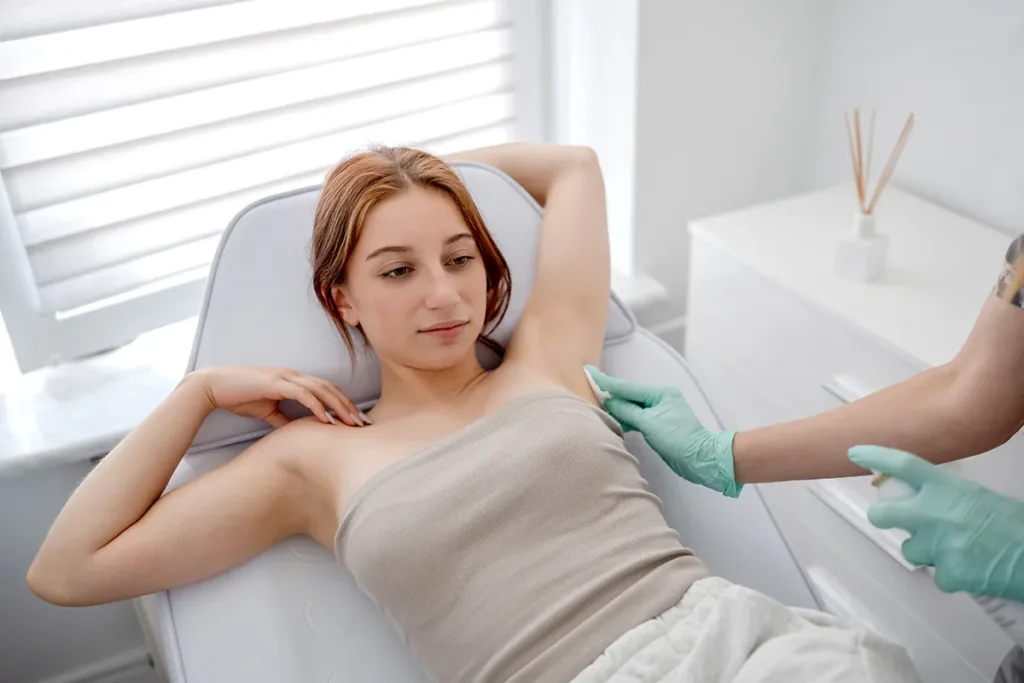 A young woman gets Brella sweat patch treatment for hyperhidrosis (excessive sweating) in a bright room