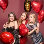 A group of smiling women holding heart-shaped balloons, celebrating valentine's day