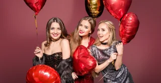 A group of smiling women holding heart-shaped balloons, celebrating valentine's day