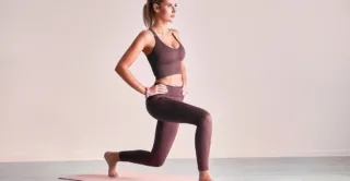 A woman in athletic clothing stretches her muscles, showing the concept of EmSculpt NEO for functional wellness